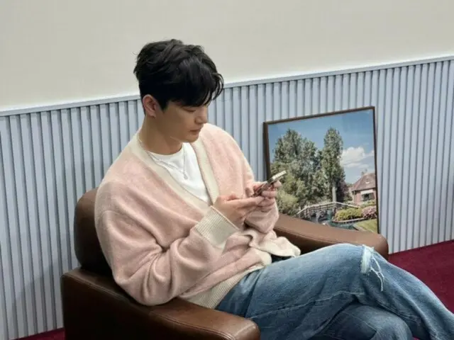 穿着粉色开衫的徐仁国看起来很放松……不知道他在智能手机上看什么？